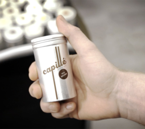 Hand hält eine silberne Dose das Haarprodukts Capille in der Hand