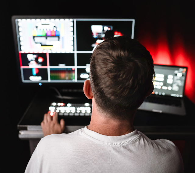 Techniker sitzt vor Monitoren und steuert Videoregie