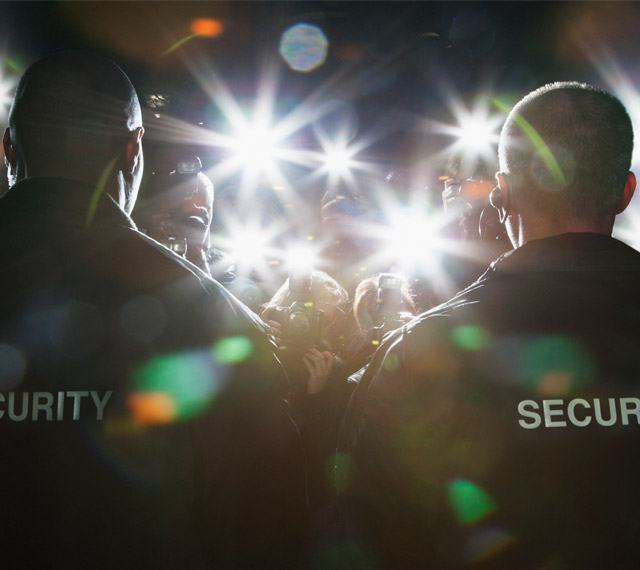 Zwei Security Männer stehen vor Pressefotografen und beschützen eine VIP Person